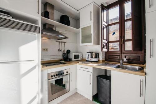 a kitchen with white cabinets and a sink at DreamStay - Oficios Apartamento in Granada