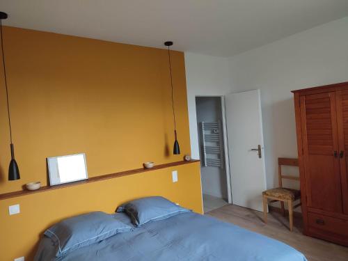 a bedroom with a blue bed and a yellow wall at Sur la Draille in Le Vigan