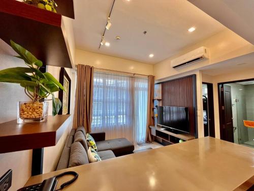 ein Wohnzimmer mit Sofa und Fernseher in der Unterkunft Twinlakes Tagaytay 1BR in Laurel