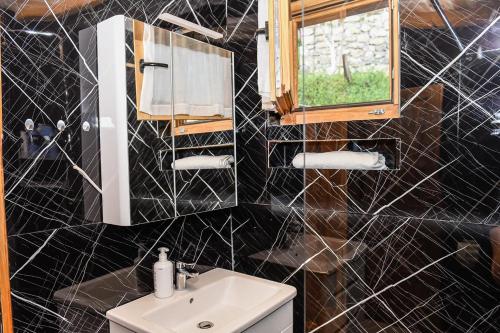a bathroom with a sink and a black tiled wall at Ostrog Wood House in Železnička Stanica Dabovići