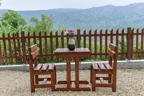 a table with two chairs and a vase with flowers on it at Ostrog Wood House in Železnička Stanica Dabovići