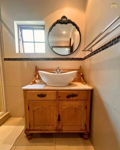 a bathroom with a sink and a mirror at Ekhaya Guest House in Ballito