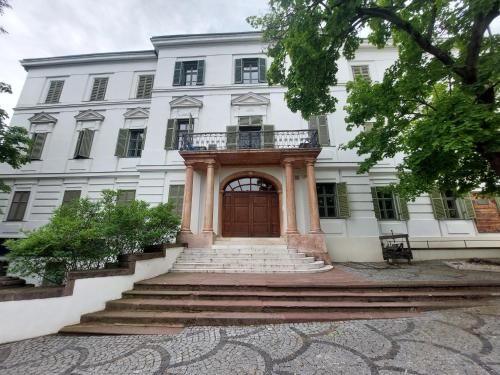 ein großes weißes Gebäude mit einer Holztür und Treppe in der Unterkunft Lakeside Heritage Apartment in Balatonfüred