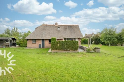 a large yard with a house with a grass yard at OV606 - Beautifully located 6-person holiday home by the water with a large garden in Ossenzijl in Ossenzijl