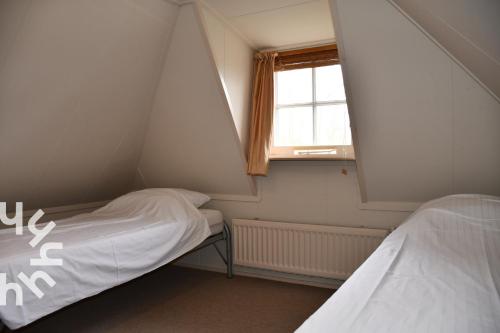 a small room with two beds and a window at OV606 - Beautifully located 6-person holiday home by the water with a large garden in Ossenzijl in Ossenzijl