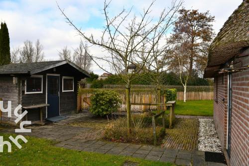 a house with a tree in the yard at OV606 - Beautifully located 6-person holiday home by the water with a large garden in Ossenzijl in Ossenzijl