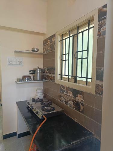 a kitchen with a stove and a window in it at Anugrahaa family Roomstay in Tiruchchirāppalli