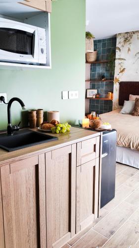 une cuisine avec un évier et un micro-ondes dans l'établissement Suites Balneo à Melun by Lilac Lane, à Melun