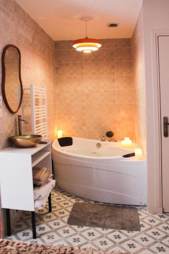 une salle de bain avec une baignoire, un lavabo et un miroir dans l'établissement Suites Balneo à Melun by Lilac Lane, à Melun