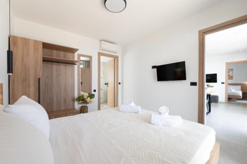 a white bedroom with a large bed and a tv at Chryselia Suites- Private Pool in Keratokampos