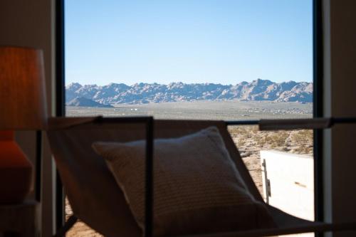 a chair in a room with a view of the desert at The Milky Way Cabin in Twentynine Palms