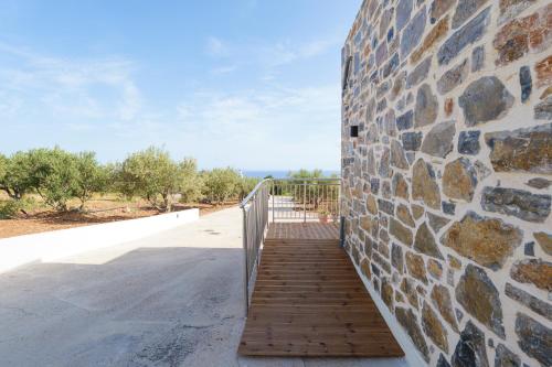 a brick wall with a wooden staircase next to a building at Chryselia Suites- Private Pool in Keratokampos