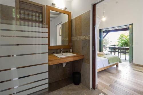a bathroom with a sink and a bed and a mirror at Jument verte in Bouillante