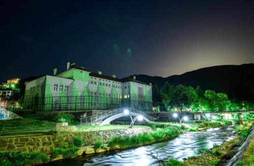 a building with a bridge over a river at night at TOMATO Apartment in Kriva Palanka
