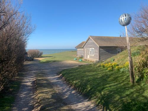 a house on a hill next to a dirt road at Seaview Room at The Boat House in Eastdean