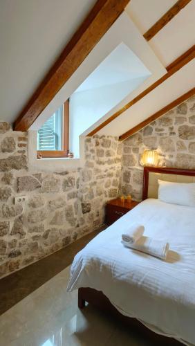a bedroom with a bed and a stone wall at Captain Roof in Kotor