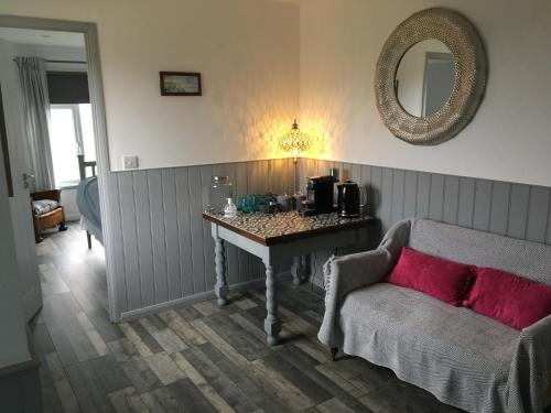 a living room with a table and a couch and a mirror at Seaview Room at The Boat House in Eastdean