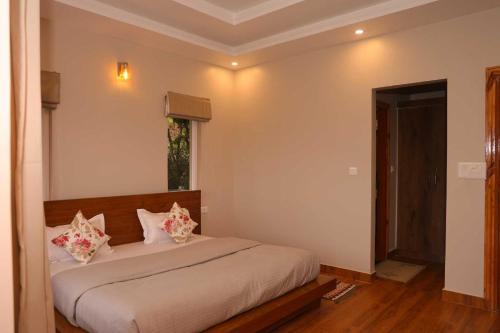 a bedroom with a bed with two pillows on it at Whispering Oaks by Happy Himalayan in Rāmgarh