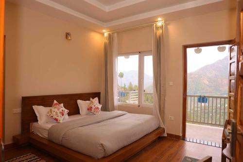 a bedroom with a bed with a large window at Whispering Oaks by Happy Himalayan in Rāmgarh