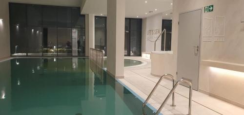 a bathroom with a swimming pool and a house at Apartament Diuna z dostępem do basenu, siłowni, hali sportowej, sauny in Gąski