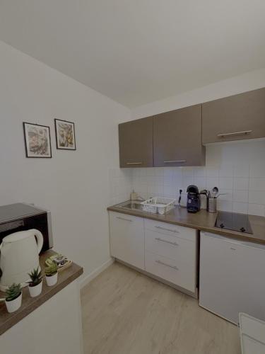 une cuisine avec des comptoirs blancs et des armoires brunes dans l'établissement Loft 4, à Saint-Gély-du-Fesc