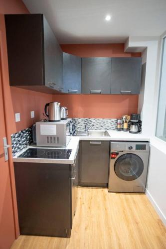 une cuisine avec une cuisinière et une machine à laver dans l'établissement Le voyageur - Appartement Avec Jacuzzi, à Cambrai