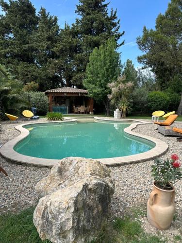 - une piscine avec un rocher dans une cour dans l'établissement Domaine de la Grande Grange, à Caderousse