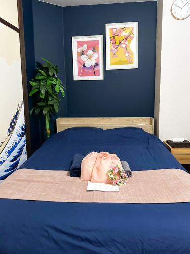 a blue bed with a bag and flowers on it at Belmont 203 3min to Station Easy Access Ueno Asakusa Skytree Sleeps 4 in Tokyo