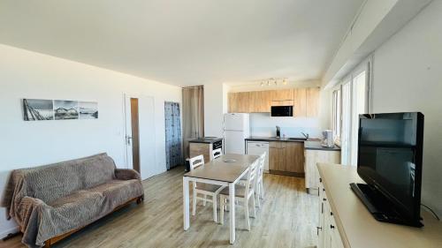 un salon avec un canapé, une table et une cuisine dans l'établissement Panoramique océan, Sables d'Or, à Saint-Jean-de-Monts