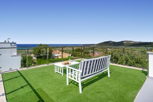 una panchina bianca su un prato con vista sull'oceano di Luxury Villa - Amazing Sea Views a Son Bou