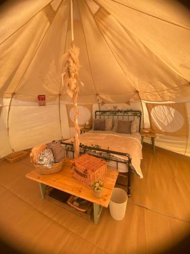 a tent with a bed and a table in it at Orchard Retreats Glamping At Black Barn Farm Norfolk in Salhouse
