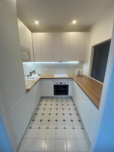 une cuisine avec des armoires blanches et un sol carrelé dans l'établissement Lisa Appartement de charme, à Cannes