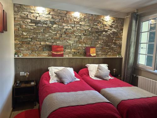 two beds in a room with a brick wall at Chambre d'hôtes de la Riaille 400 m de la dolce via in Le Cheylard