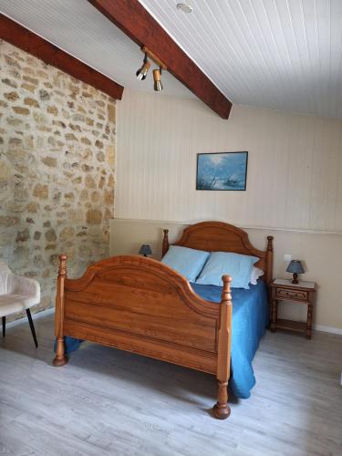 - une chambre avec un lit en bois et un mur en pierre dans l'établissement Les Hauts Benquey, à Mérignas