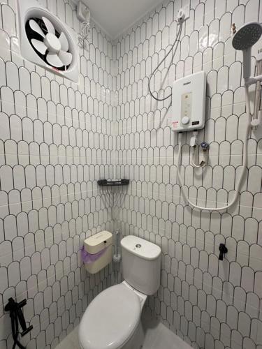 a white tiled bathroom with a toilet and a sink at Homestay Ayuni in Kuala Terengganu
