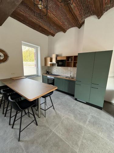 a kitchen with a wooden table and green cabinets at Les gîtes de la ferme du moulin in Binche