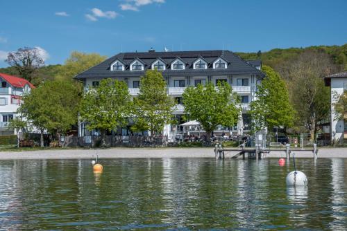 uma casa na costa de um corpo de água em Ammersee-Hotel em Herrsching am Ammersee