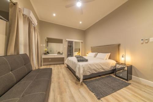 a bedroom with a bed and a couch at Room 6 - LEO Sky Guest House in Simondium