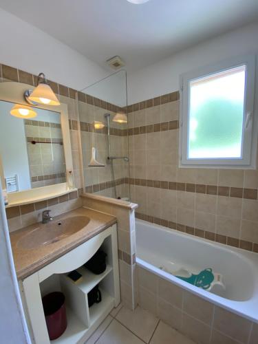 une salle de bain avec une baignoire, un lavabo et un miroir dans l'établissement Duplex dans Village Vacances 6 personnes - Ardèche, à Grospierres