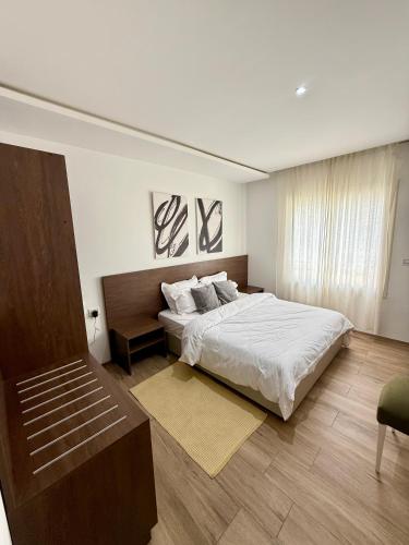 a bedroom with a large bed and a chair at Appartement moderne à l Aouina avec WiFi parking et proche aéroport Tunis Carthage in Ariana
