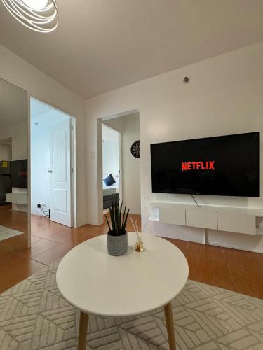 a living room with a white table and a tv at Modern Minimalist Luxe Retreat 2 Bedroom with parking in Manila