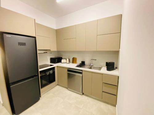 a kitchen with white cabinets and a black refrigerator at Sea view Penthouse Universal Residences in Nea Paphos