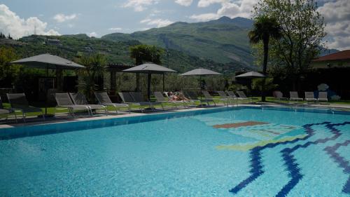 a large swimming pool with chairs and umbrellas at Residence Verdeblu in Arco