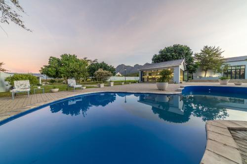 a pool with blue water in front of a house at Room 6 - LEO Sky Guest House in Simondium