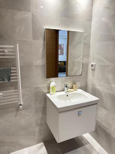 a bathroom with a white sink and a mirror at Appartement moderne à l Aouina avec WiFi parking et proche aéroport Tunis Carthage in Ariana