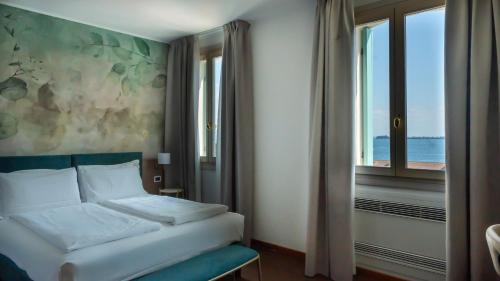 a bedroom with a bed and a window at Gardone Palace Hotel in Gardone Riviera