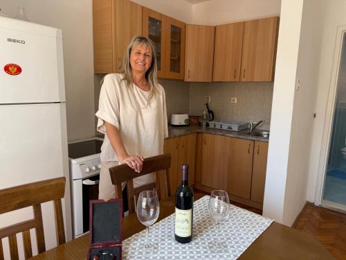 a woman standing in a kitchen with a bottle of wine at Apartments Aleksić Old Town in Budva