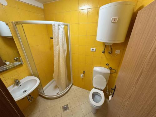 a yellow bathroom with a toilet and a sink at Apartma Studio Enej Piran in Piran