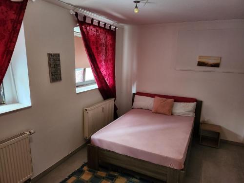 a small bedroom with a bed with red curtains at Halle, Bestes in Preis- Leistung- Lage, City, EG, 84 qm, SD, 1- 3 Doppelzimmer, extra für sie kostenlose TV Lounge extra Küche u Bad bis 6 Personen in Halle an der Saale