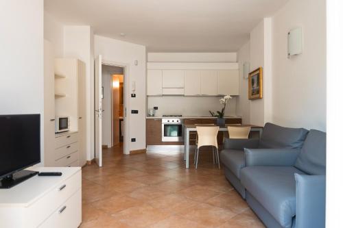 a living room with a blue couch and a kitchen at Hotel Ristorante La Quartina in Mergozzo